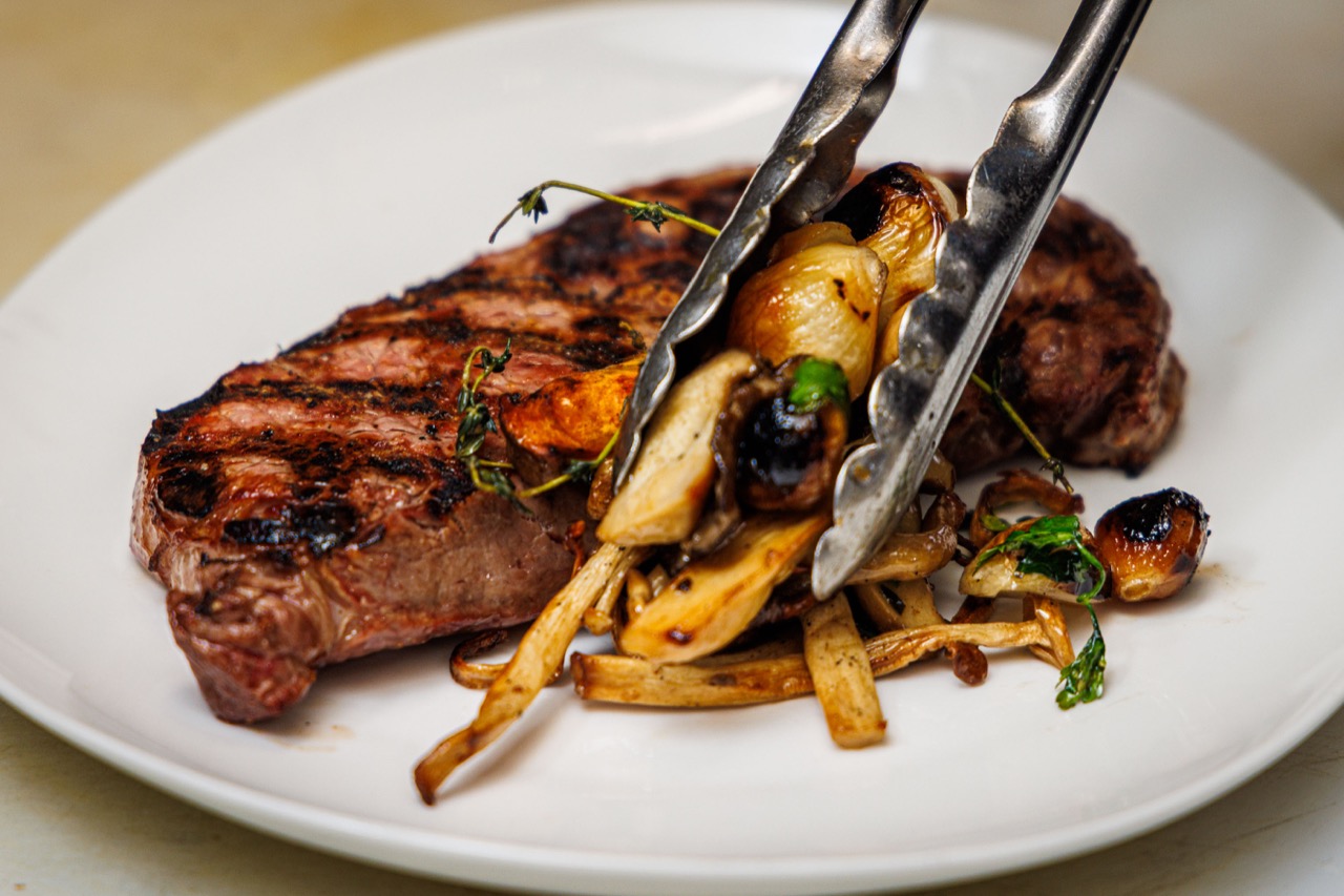 Steak being plated by the culinary team at The Alexander