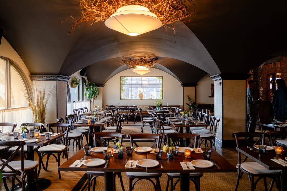 The Alexander dining room with vaulted ceiling, set tables, and warm chandelier light