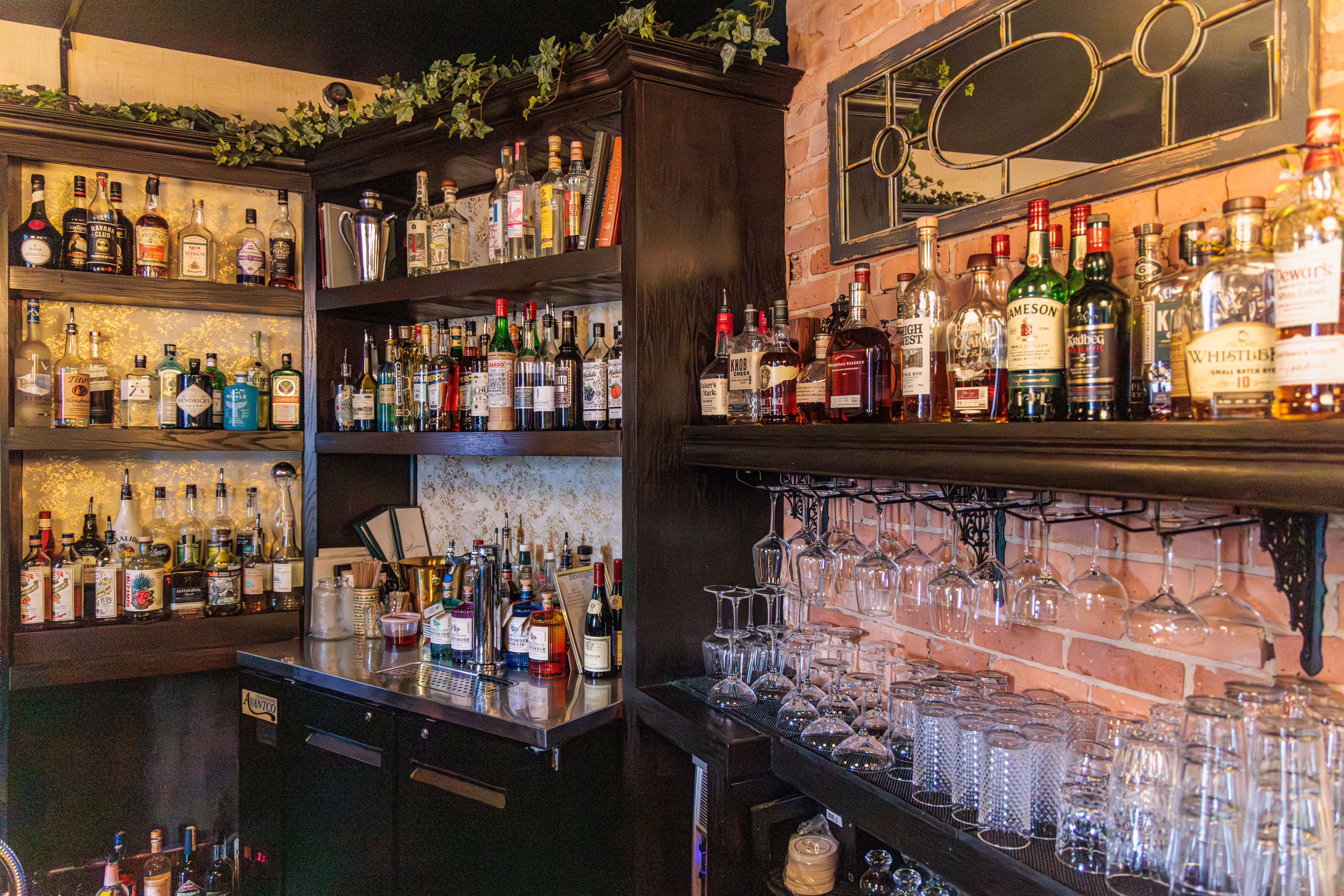 Bar shelves with spirits, glassware, exposed brick, and stained glass details